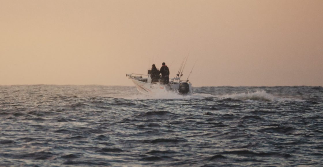 Offshore fishing boat cruising in the Pacific Ocean at sunset