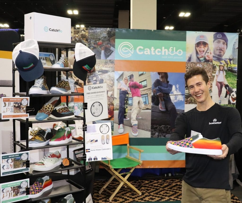 Angler holding shoe in front of the Catchflo booth at the Fly Fishing Show Denver