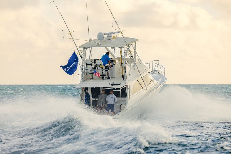 Sportfishing boat heads offshore with the captain driving and anglers looking out from the back of the boat
