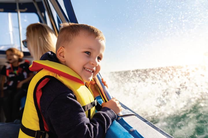 Boy wearing a life jacket on a boat.