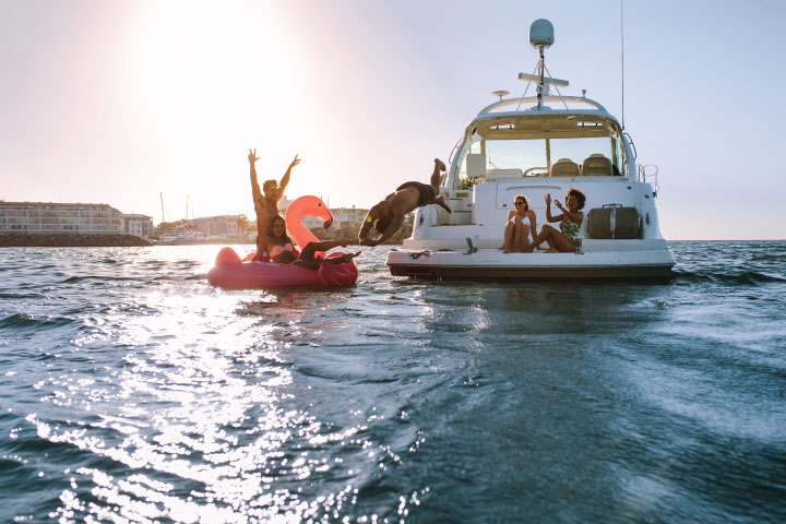 A group of friends swimming off a yacht.