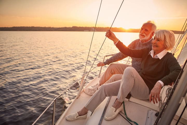 Retired couple on a sailboat watching the sunset.