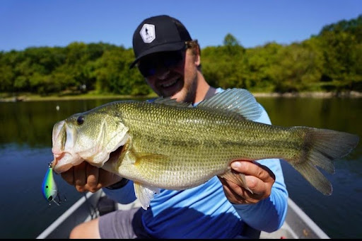 Fisher holding bass caught on a shallow squarebill crankbait