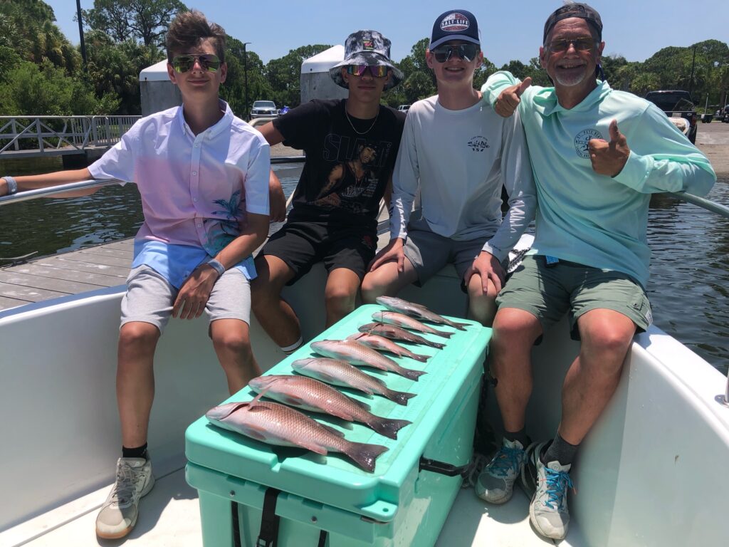 Fishing clients posing with their catch on a cooler from a charter in St. Petersburg, Florida
