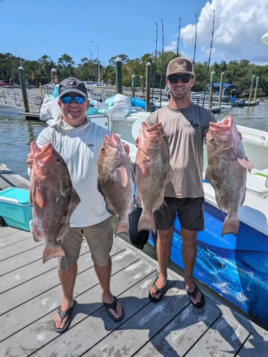 Fishermen hold red grouper caught offshore from Madeira Beach in Tampa, Florida