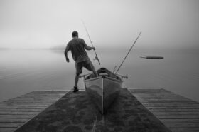 Angler stepping out of a small wooden fishing boat with rod in hand