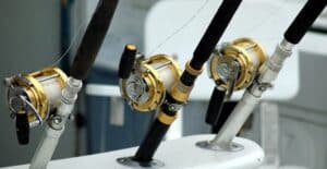 Detailed view of fishing rods with gold reels on a boat, ideal for angling enthusiasts.