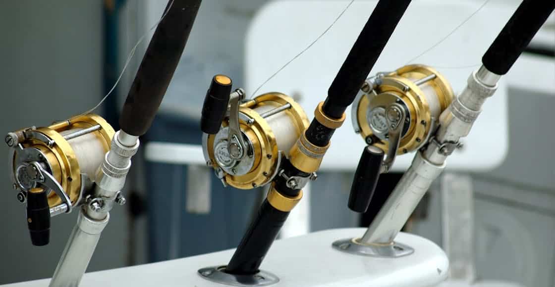 Detailed view of fishing rods with gold reels on a boat, ideal for angling enthusiasts.