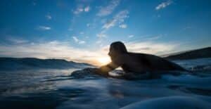 A man preparing to surf at sunset along the scenic Argentine coastline with waves crashing.