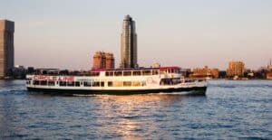 Circle Line ferry cruising in front of New York City skyline during sunset.