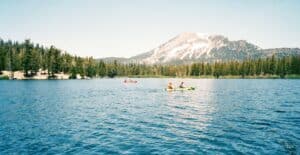Explore the serene beauty of Mammoth Lakes with kayakers against a mountain backdrop.