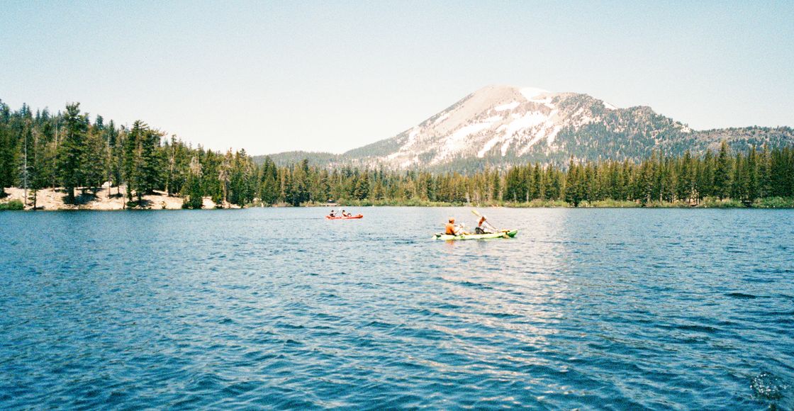 Explore the serene beauty of Mammoth Lakes with kayakers against a mountain backdrop.