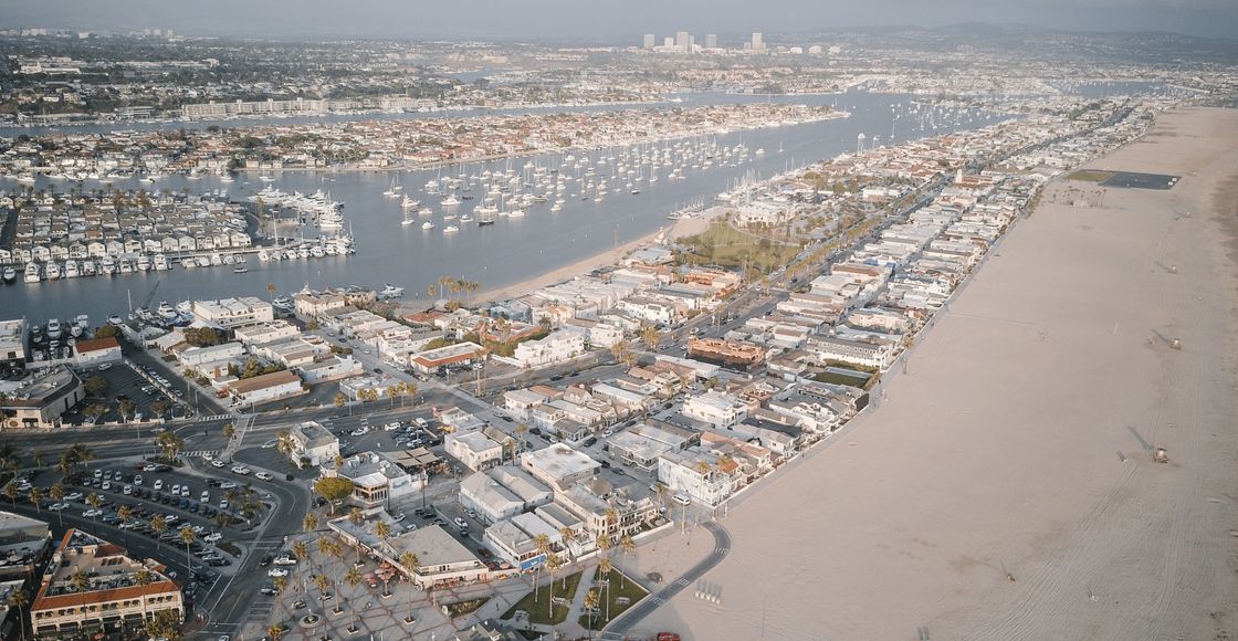 Aerial cityscape showcasing a coastal area with marina and sandy beach.