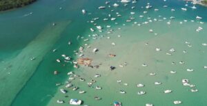 Discover a vibrant aerial view of a bay filled with motorboats and emerald waters, perfect for travel enthusiasts.