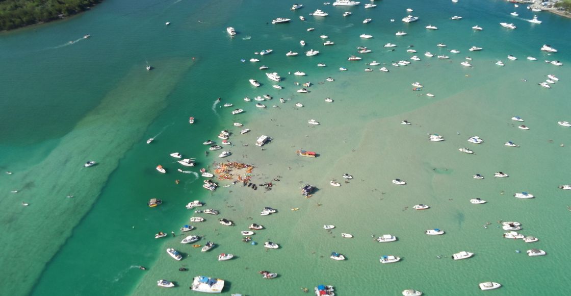 Discover a vibrant aerial view of a bay filled with motorboats and emerald waters, perfect for travel enthusiasts.