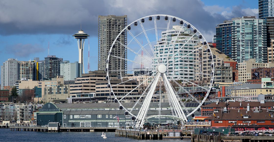Iconic view of Seattle's skyline with the Space Needle and Great Wheel on a cloudy day.