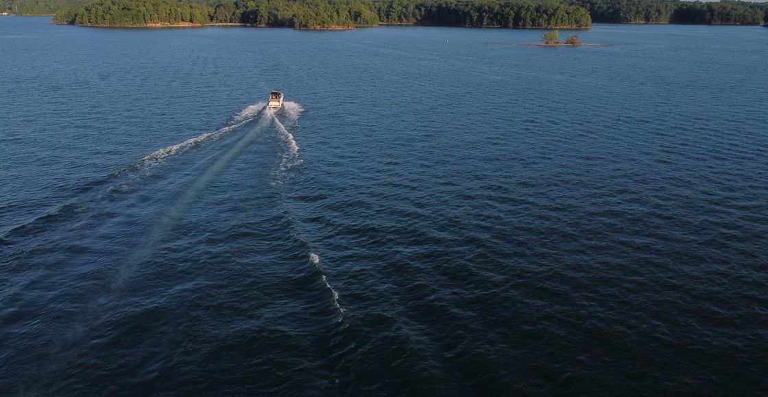 Captivating aerial view of a boat cruising on Lake Lanier surrounded by lush greenery in Georgia.