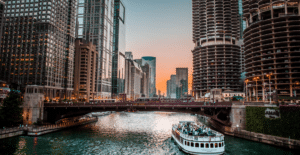 A mesmerizing view of the Chicago River with skyscrapers and a boat during sunset.