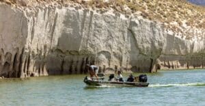People enjoying a boat ride along striking limestone cliffs in a scenic outdoor setting.